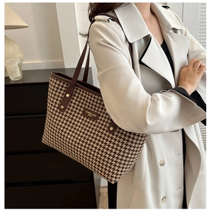 Detail showing classic houndstooth pattern and leather trim on a stylish tote bag