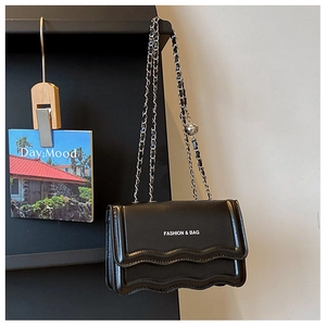 Detail of fashion chain bag with black leather wavy flap and silver metallic strap