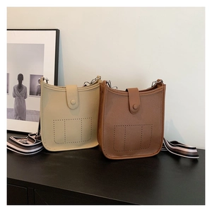Close-up of litchi texture leather bucket bags with perforated H design and striped straps