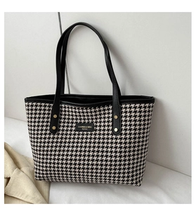 Detail of houndstooth fabric texture and leather logo on the stylish tote bag