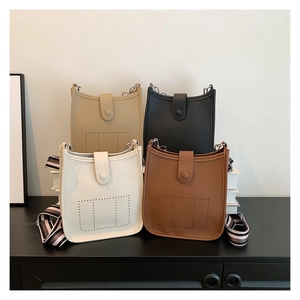 Detail of four colorful crossbody bags with perforated leather and striped straps