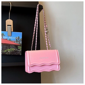 Detailed view of pink wavy flap crossbody bag with metal chain and fashion text
