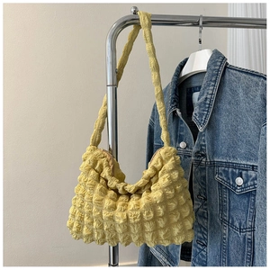 Gros plan du sac fourre-tout jaune texturé suspendu avec une veste en jean