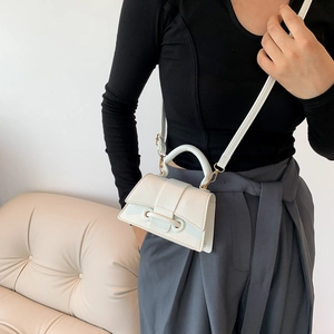 Mini white leather hourglass handbag with top handle and strap worn by a model