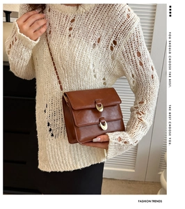 Detail of vintage brown PU leather crossbody bag featuring gold buckles and chain strap