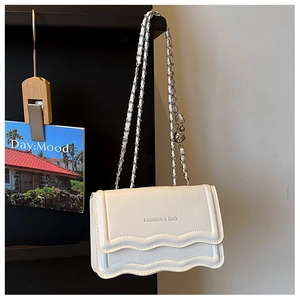 Close-up of wave textured white PU leather crossbody bag with silver chain strap