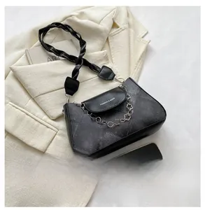 Détail d'un sac bandoulière noir à texture géométrique avec chaîne florale chic