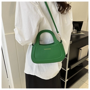 Detail of green crossbody bag with top handle and gold Fashion & Bags lettering