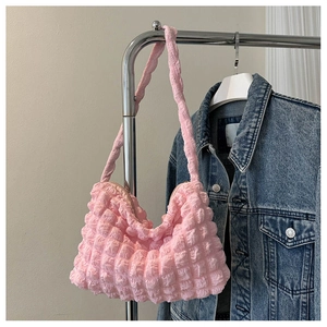 Gros plan du sac bandoulière rose en tissu gaufré suspendu sur un cintre en métal