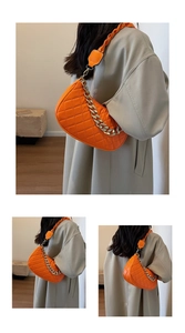 Dettaglio borsa trapuntata arancione brillante con catena dorata e tracolla in pelle