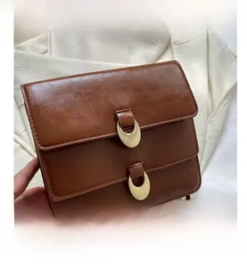 Detail of brown vintage flap bag showing glossy leather texture and double gold buckles