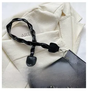 Détail de la bandoulière tressée et de la chaîne à fleurs métalliques sur le sac noir rétro