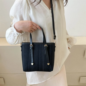 Elegant black vertical woven tote bag with adjustable strap shown on a model