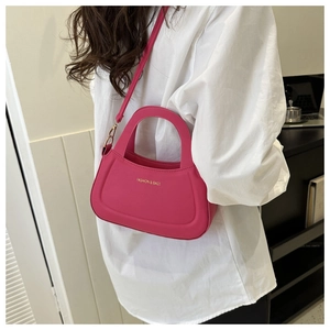 Detail view of pink crossbody bag with golden FASHION & BAGS text and metal hooks