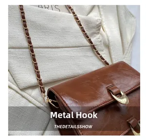 Detail of vintage brown leather handbag with gold chain strap and moon clasp hardware