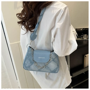 Détail du sac bandoulière en denim bleu clair avec chaîne fleurie argentée et matelassage