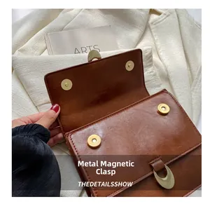 Close-up of golden magnetic buckle on vintage brown leather handbag with artsy props