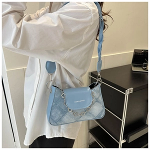 Détail du sac à bandoulière en cuir bleu clair et denim avec chaîne fleurie argentée