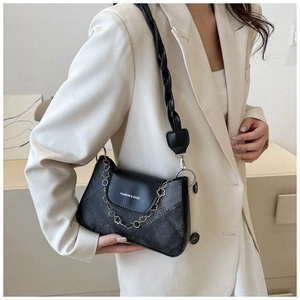 Détail d'un sac sous le bras minimaliste avec bandoulière tressée et chaîne fleur