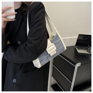 Sac à bandoulière tissé bleu et blanc avec large sangle, porté sur un blazer noir