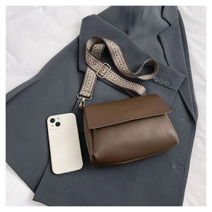Detail of dark brown matte leather tote bag with wide geometric pattern strap