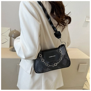 Détail du sac à bandoulière noir matelassé avec chaîne florale et sangle tissée chic