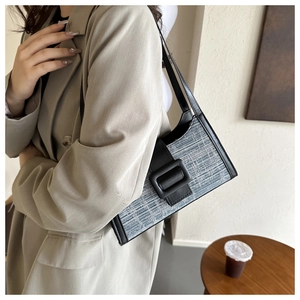 Gros plan sur le sac baguette en tweed bleu avec bordure en cuir noir et boucle mate
