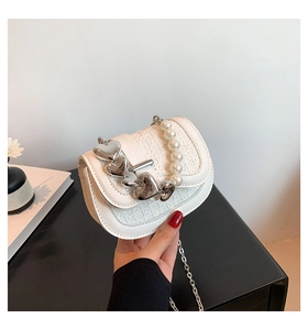 Detail van witte geweven minitas met parelhandvat en hartvormige metalen sluiting