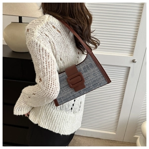 Détail du sac sous le bras en tissu bleu marine avec bordure en cuir et boucle carrée décorative