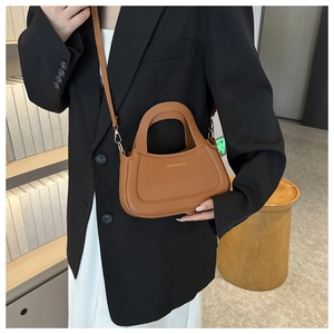 Detail of caramel faux leather bag with gold hardware on a black blazer outfit