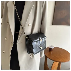 Detailed view of a black glossy PU crossbody bag with dual golden crescent buckles