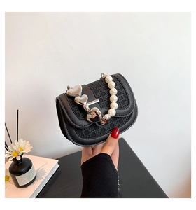 Detail van zwarte geweven mini-tas met parelhandvat en drie zilveren hartvormige hangers