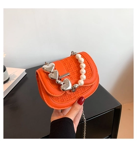 Detail van oranje geweven minitas met hartsluitingen, parelhandvat en metalen ketting