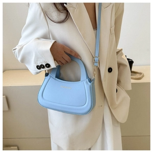 Detail of light blue semi-circular crossbody bag with golden hardware and adjustable strap