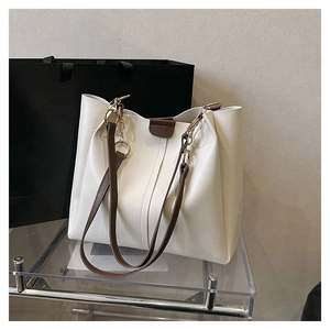Detail of off-white leather tote bag with brown straps and elegant gold chain accents