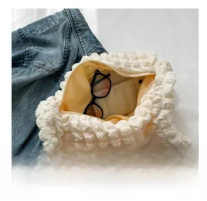 Detailed view of white pleated handbag interior showing capacity with sunglasses inside