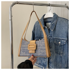 Détail du sac baguette en tweed avec tissage bleu et bordure en cuir camel sur un cintre