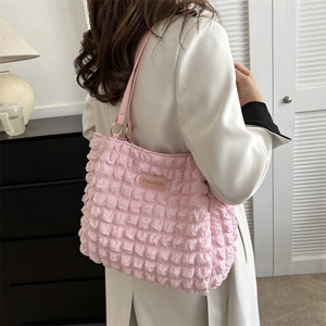 Chic light pink bubble textured tote bag with leather straps worn by a model