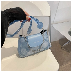 Détail du sac à bandoulière bleu clair texture denim avec motif losange et chaîne florale