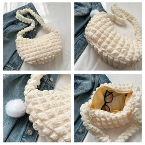 Detailed views of creamy white bubble textured hobo bag with plush ball pendant
