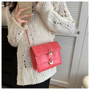 Detail of coral pink crossbody bag featuring dual-layer flap and golden moon-shaped buckles