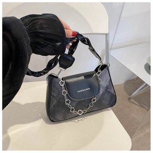 Détail du sac bandoulière en denim noir et cuir avec chaîne à fleurs et bandoulière