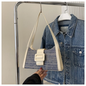 Détail d'un sac sous le bras tissé bleu et crème suspendu avec fond en jean bleu