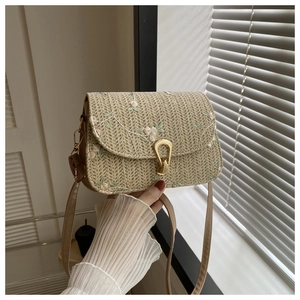 Detail einer Stroh-Handtasche mit Blumenstickerei und goldenem Tropfenverschluss