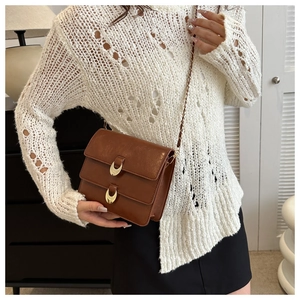 Close-up of brown textured leather shoulder bag featuring gold hardware and chain strap