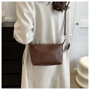 Detail der braunen Schultertasche mit Krokodilmuster und Vintage-Metallnieten