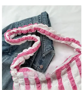 Detail of pink and white striped pleated shoulder bag with decorative ruffle strap style