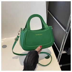 Detail of green crescent handbag with gold hardware and adjustable strap on white background
