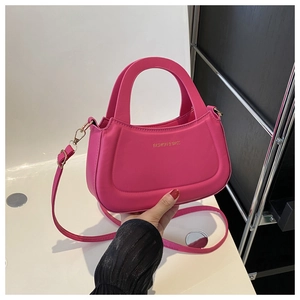 Detail of a magenta half-moon bag featuring gold lettering and detachable shoulder strap