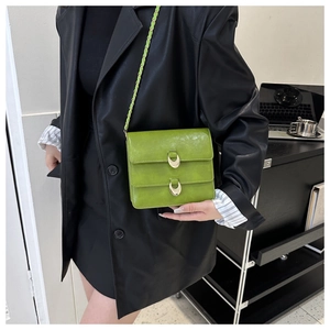 Detail of lime green shoulder bag with gold buckles worn over a black leather jacket